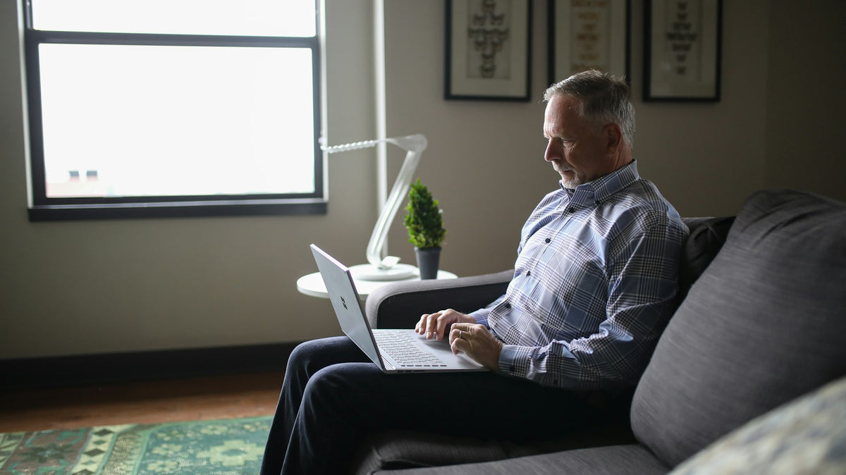 Man sitting on a couch working on a laptop
